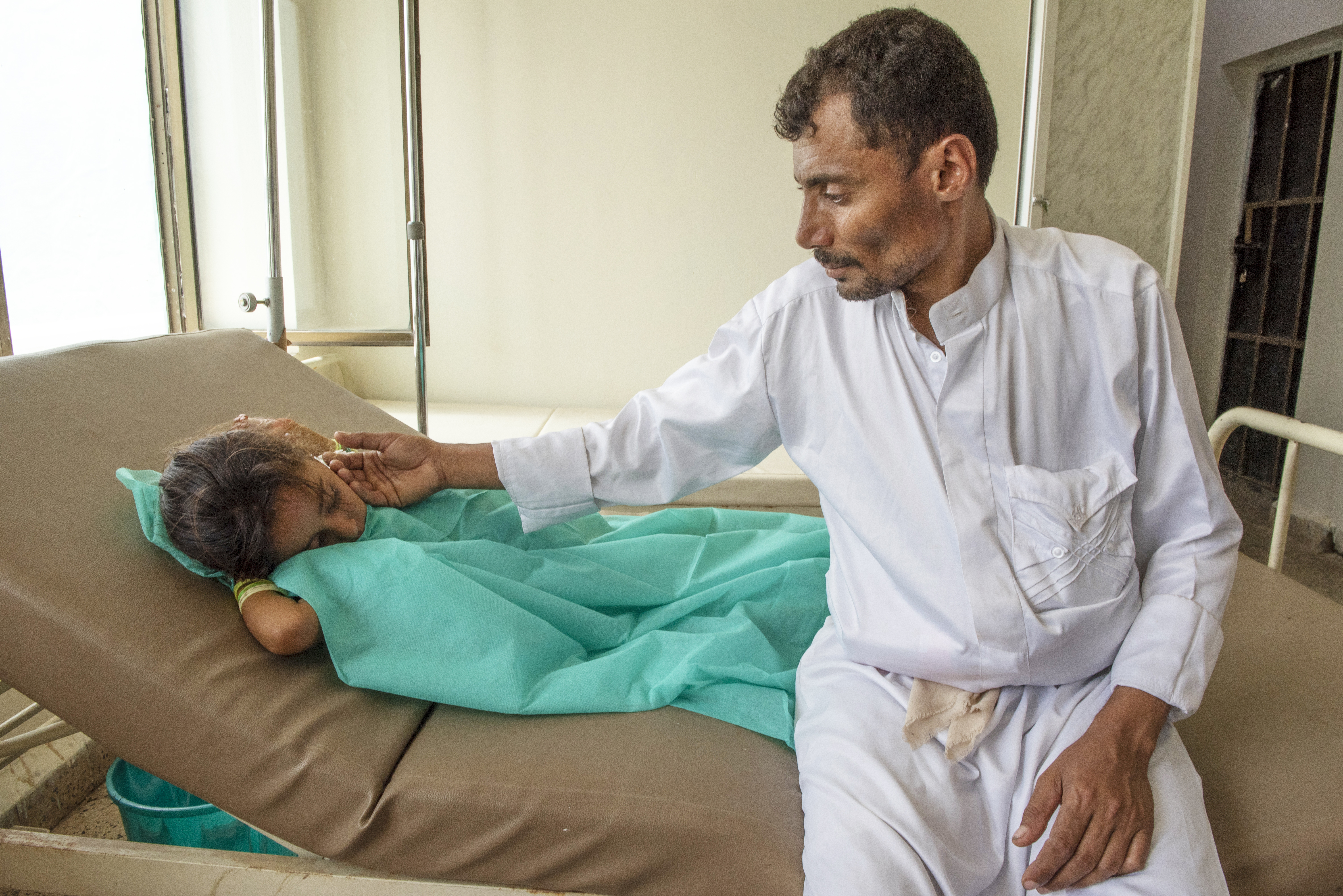 Abdullah sits with his 7-year-old daughter Nehan as she receives treatment for cholera at a Mercy Corps-supported health clinic in Yemen. More than 1 million cholera cases have been reported since April 2017. Photo: Ezra Millstein/Mercy Corps