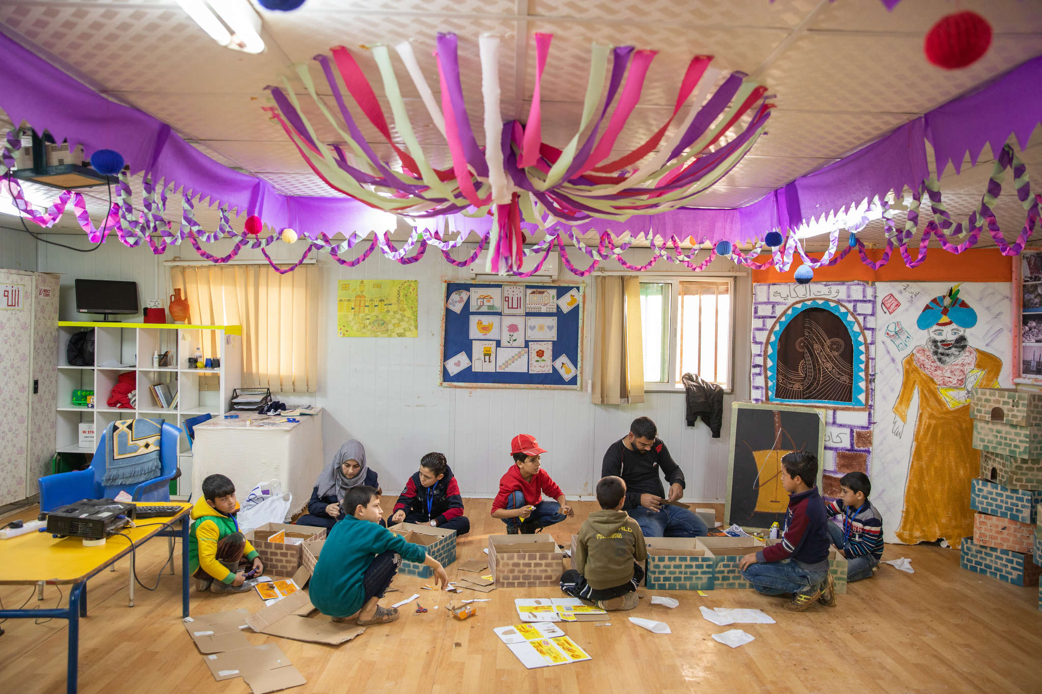 Mohammad enjoys learning about Syrian culture. Here, he makes a house out of cardboard, decorating it with what he’s learnt about Syrian traditions, art and values.