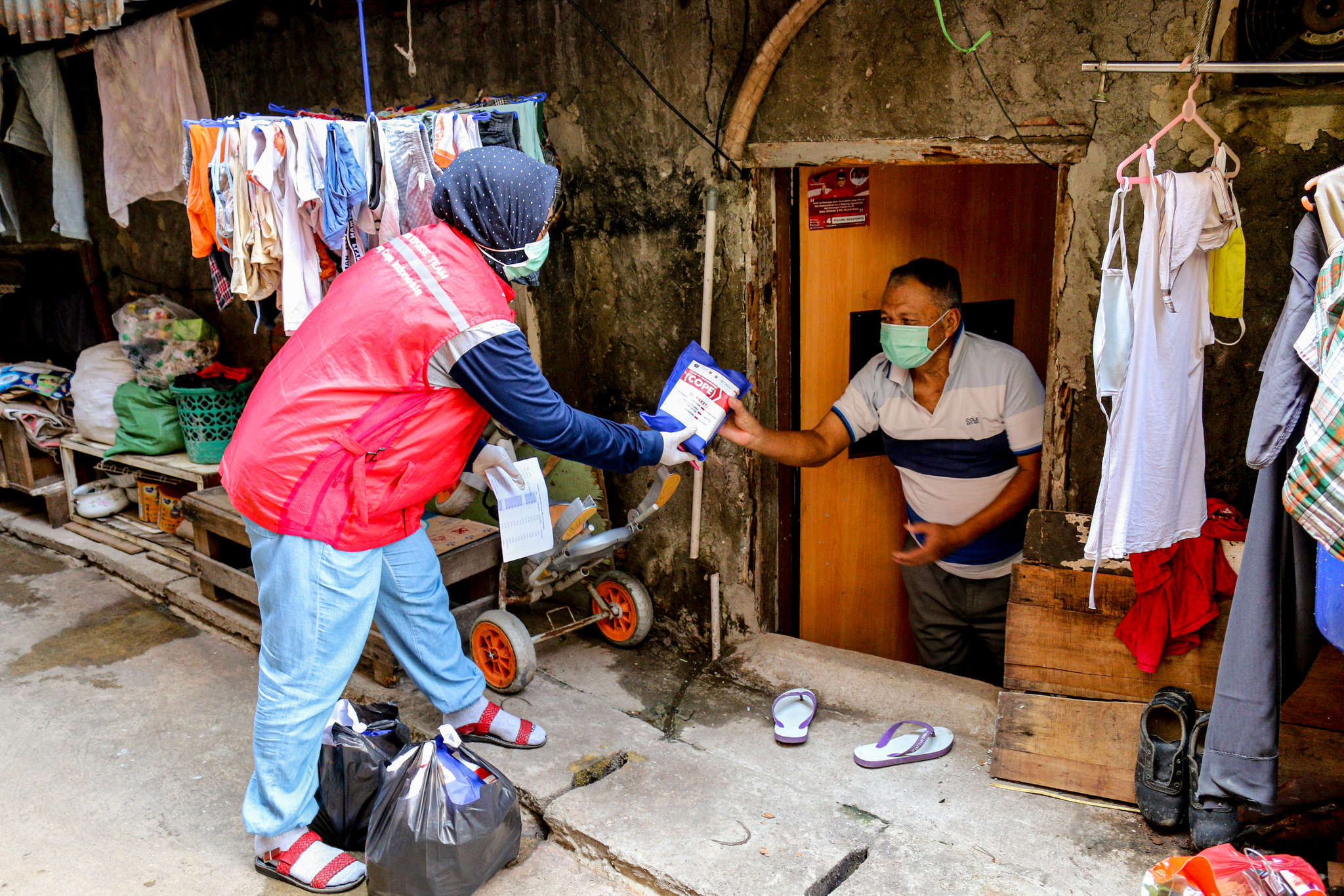 A Mercy Corps staff team member hands someone a hygiene kit during a door to door community outreach event in Jakarta Province.