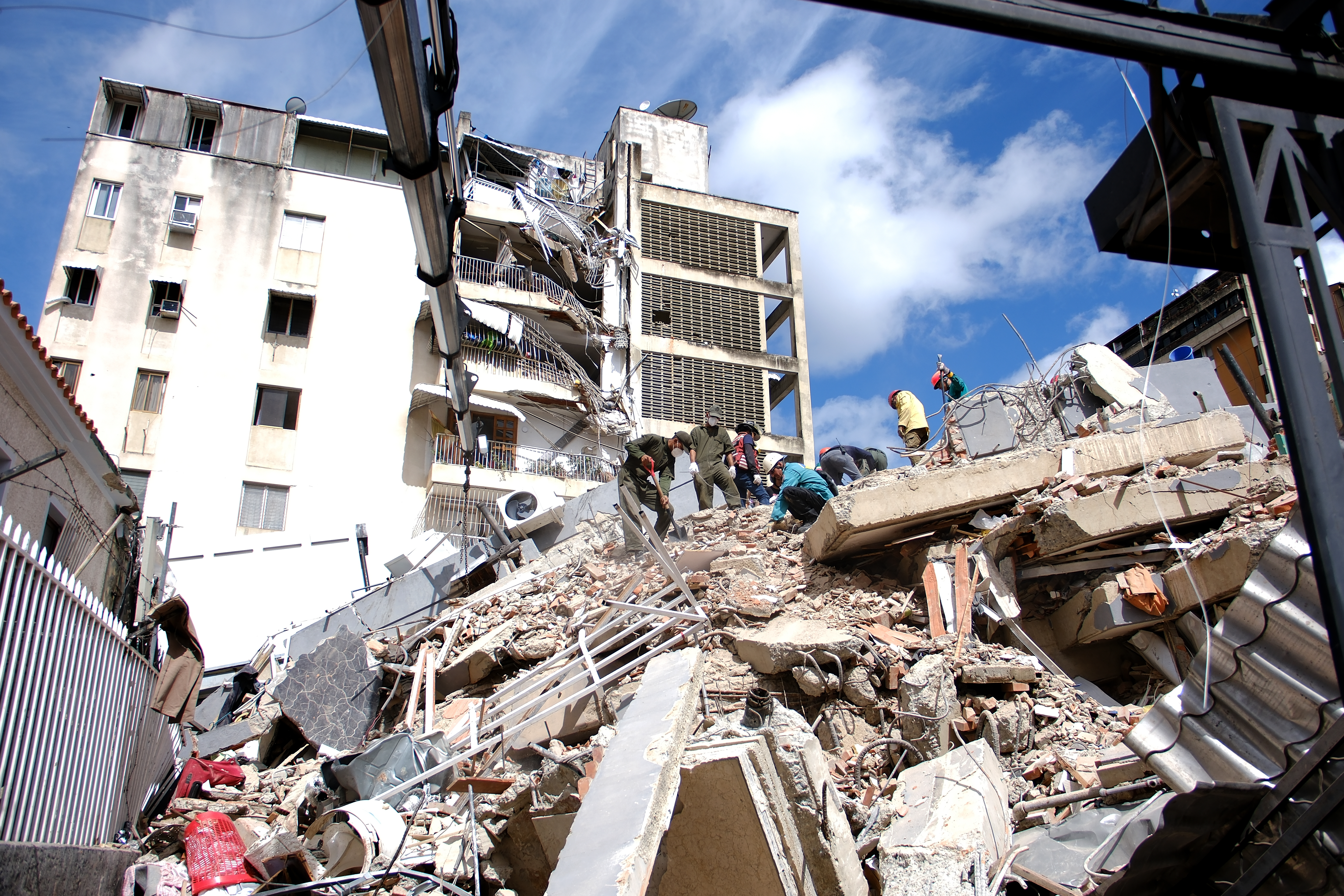 Venezuelan emergency crews work through rubble of building.