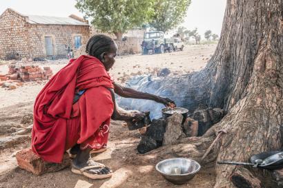 A Sudanese mother boils sorghum for her children.