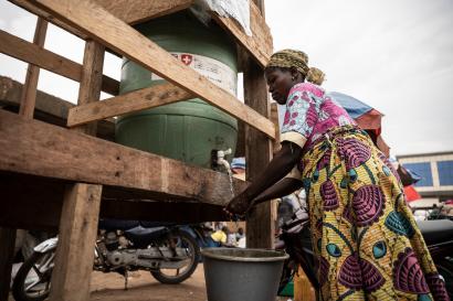 DRC woman washing hands at a water station.