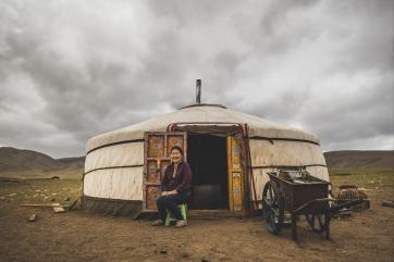 Sugar sitting outside a yurt beneath a cloudy sky