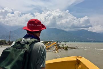 Mercy corps employee surveying damage to a bridge, which is underwater