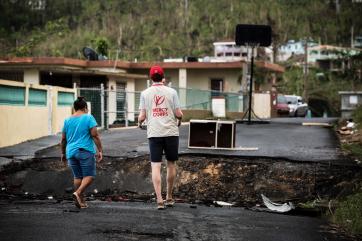 A mercy corps team member carries a tray of food into a village that was hit hard by hurricane maria