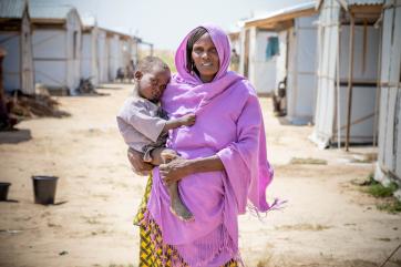 A woman holds her young son outside in a displacement camp in nigeria.