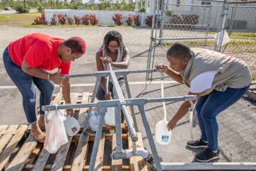 Three mercy corps colleagues fill up water from spigots.