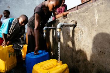 Young people fill water vessels.