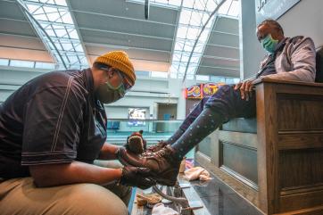 A shoe shiner works on the boots of a customer.