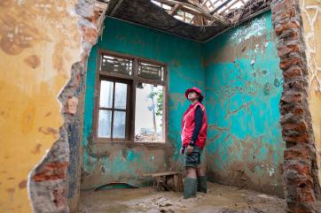 A mercy corps team member surveying the inside of a building damaged by flooding. 