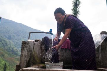 A person using a water spigot to clean fabric