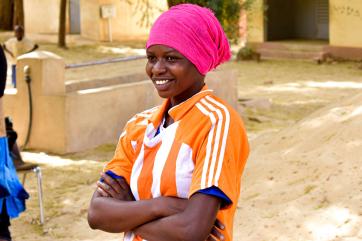 A smiling person stands with arms folded.