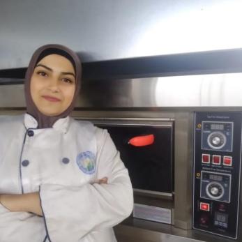 A business owner leaning on a oven for making baked goods.