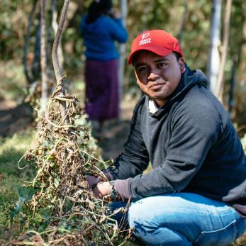 Man in guatemala wearing a red mercy corps hat in a field