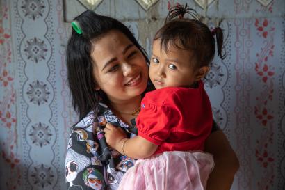 Mother holds her infant daughter inside their home in indonesia