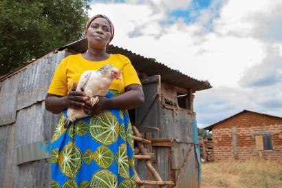 Patricia nthenge holding one of her chickens.