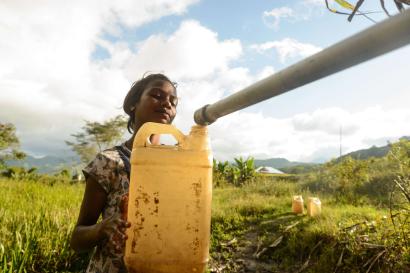 A person in timor leste filling up a jerrycan with water from a pipe.