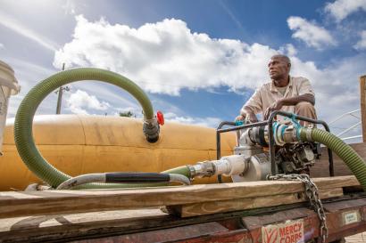 A volunteer sitting atop a potable water truck.