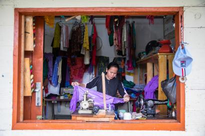 A view through a window into a shop with a woman working with fabrics.