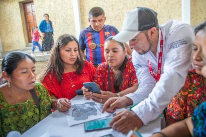 Guatemalan women and mercy corps program facilitator work over a map.