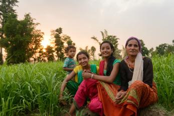 Sarmila sitting with her family in a green rice paddy