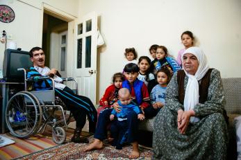 A grandmother sits with her grandchildren and one adult son, who uses a wheelchair, in turkey