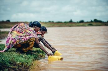 Two women filling yellow jerry cans from a lake in ethiopia
