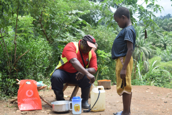 A man treats water with powder while a boy looks on in dr congo