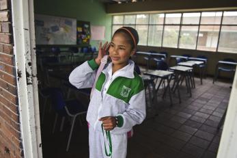 A young person stands in a doorway to a classroom.  