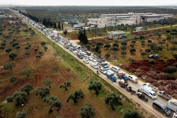 Syrians fleeing violence toward camps in northwest syria sit in traffic on a clogged road.