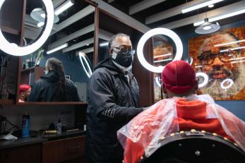 A barber cuts the hair of a customer.