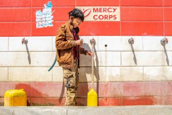 A young person fills a jerry can at a water point which was built by mercy corps. 
