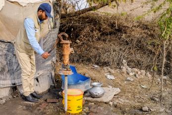 A person inspecting a damaged handpump, used to access local water in balochistan, pakistan.