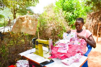 A person gathering materials at their sewing station.