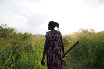 Ugandan woman stands in field of sesame.