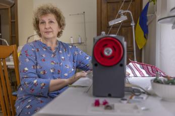 Ukrainian woman sitting at sewing machine.