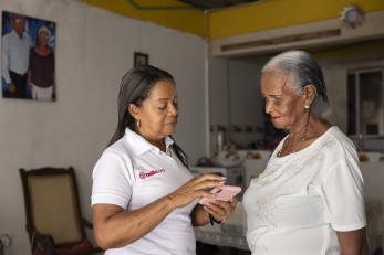 Mercy corps team member shares the latest emergency response tools and practices during a community visit with san andrés resident, maría esther.