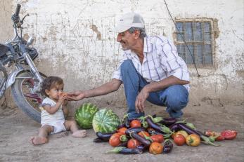 Syrian granddaughter and grandfather eating watermelon