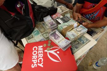 Hands holding a calculator near a stack of cash