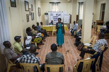A group sits in a circle around a presenter at a public health training in liberia