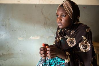 A young woman sits with her hands touching in front of her in nigeria
