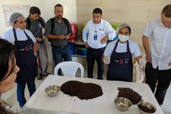 A group of people gather around a table covered in coffee beans.