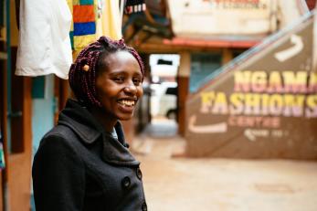 Kenyan woman smiling in a marketplace.