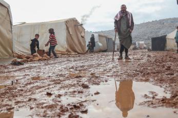 A person stands on a muddy road after a heavy rainstorm in salah al-din camp.