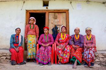 A group of female farmers siting together outside a building.