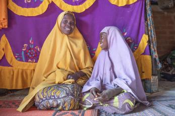 A mother her daughter sit in their home built by mercy corps.