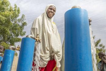 A person using a water spigot at a borehole.