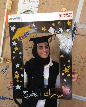 A young person holds a frame celebrating her educational achievements.
