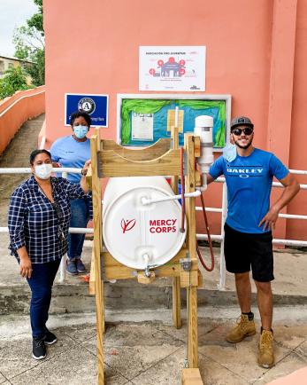 Members of the mercy corps puerto rico team pose with a hand washing station they constructed, delivered, and installed.