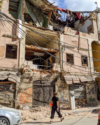 A person walking among rubble in a city. 